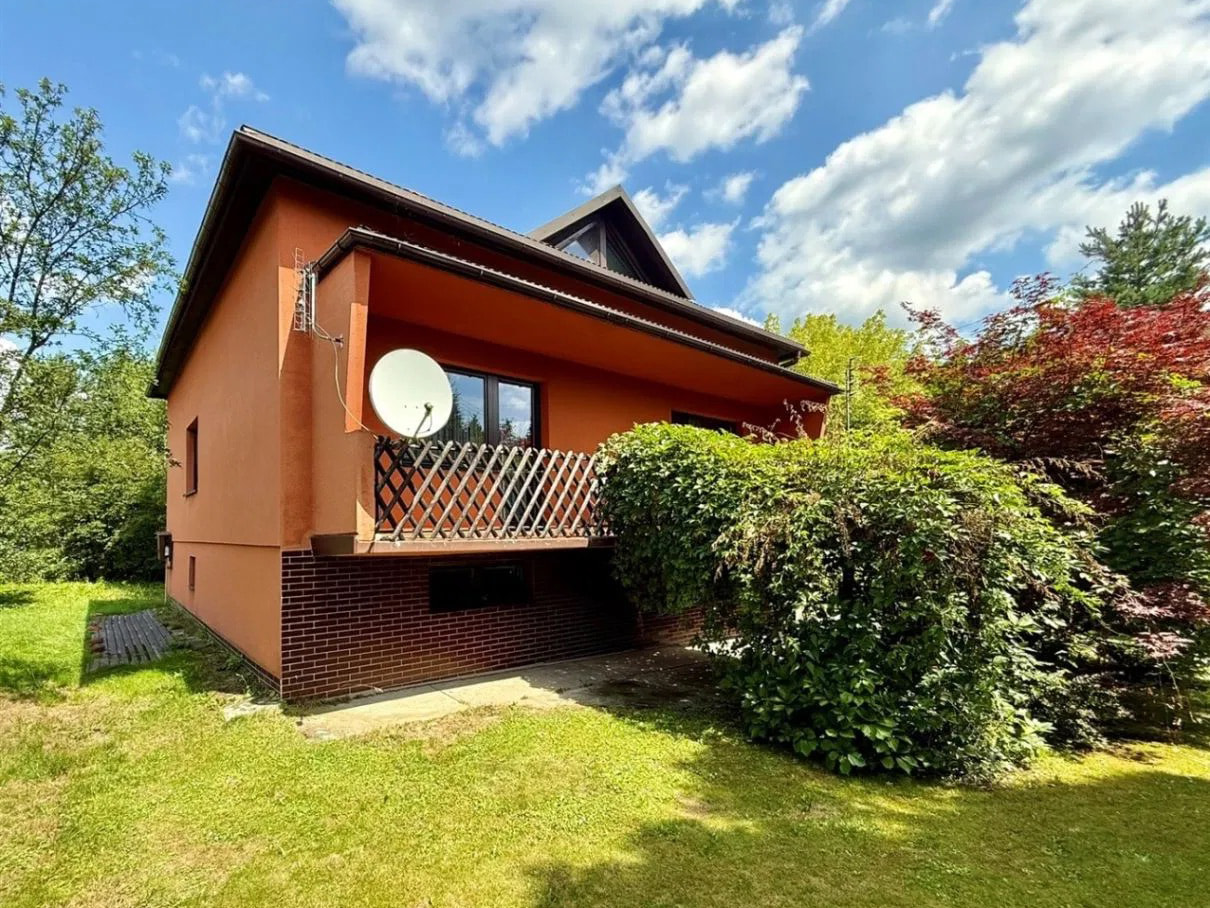 This exterior view captures a charming detached house with a vibrant orange stucco finish, complemented by a contrasting dark brick foundation. A prominent satellite dish is mou...
