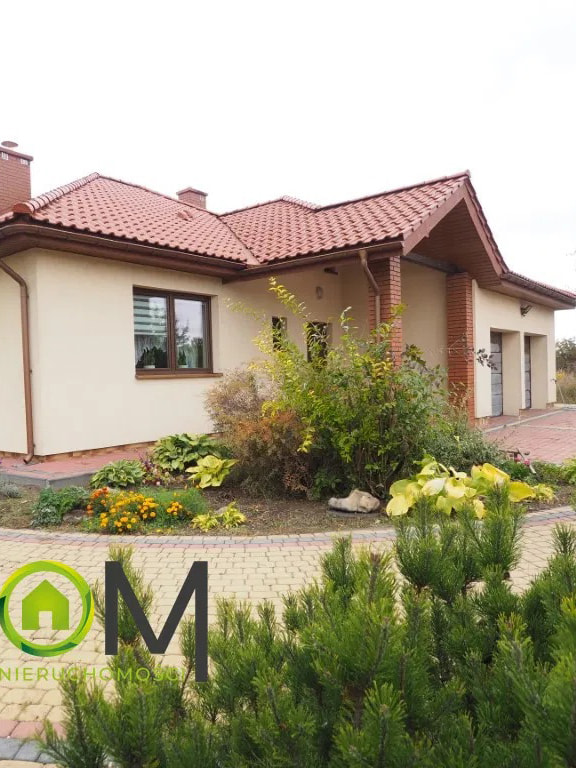 This inviting outdoor view showcases a single-story home with a warm, neutral facade and a classic red tile roof. The property features a well-maintained front yard with a varie...