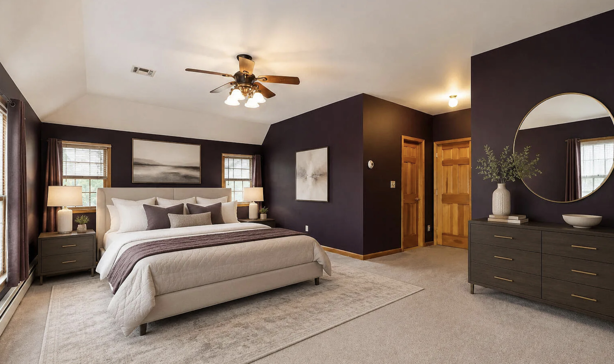 This spacious bedroom features a sophisticated ambiance with deep plum walls complemented by a large, neutral-toned rug. The king-sized bed is dressed in crisp white linens and...