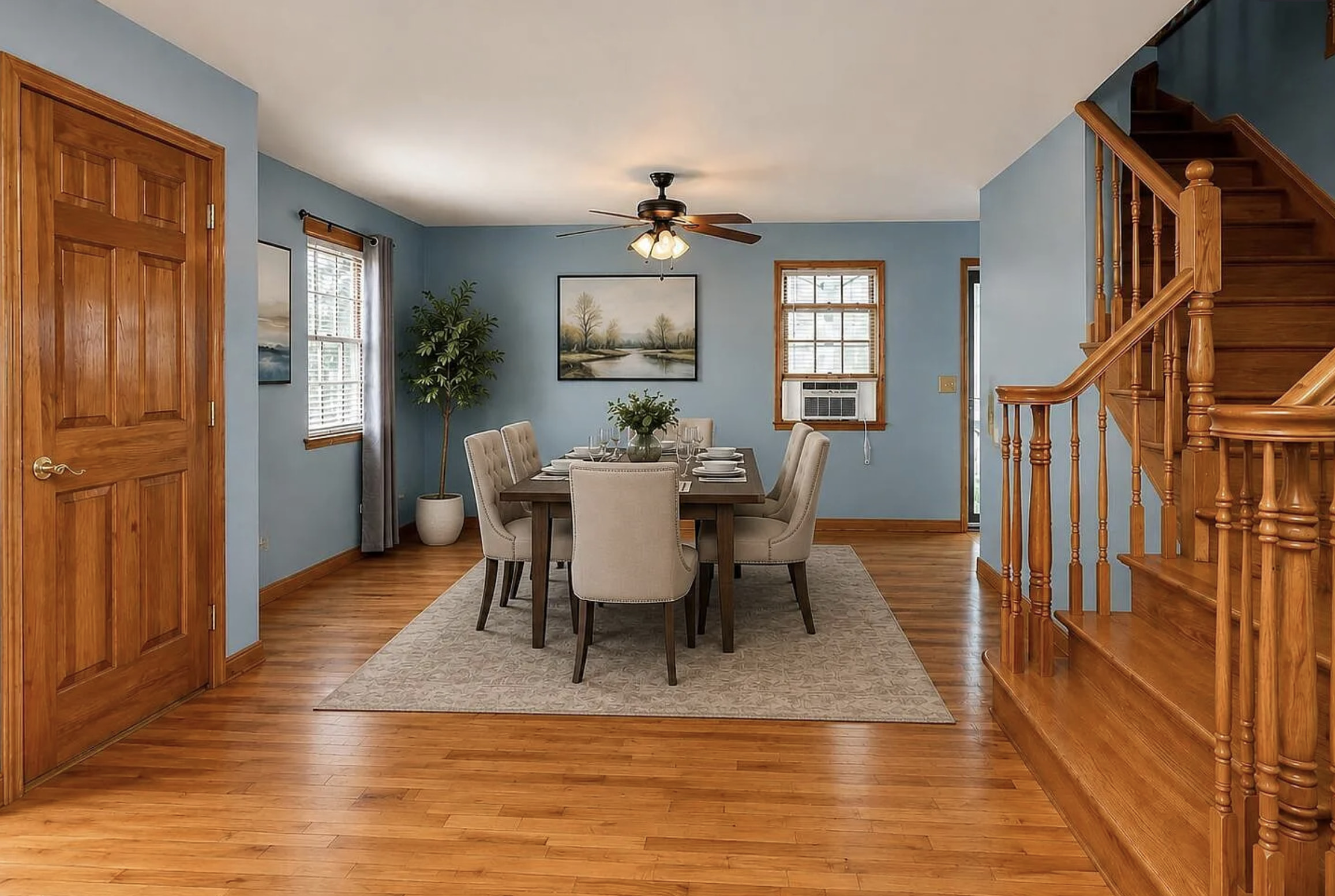 This inviting dining room features a formal dining set with six upholstered chairs around a dark wood table, all centered on a patterned area rug. The walls are painted a serene...