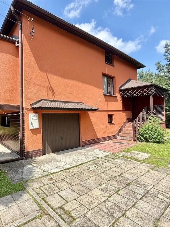 This exterior view showcases a two-story detached house with an eye-catching terracotta-colored stucco facade, accented by dark brown trim and roofing. The property features a p...